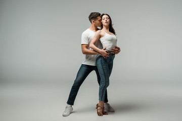 dancers with closed eyes dancing bachata on grey background