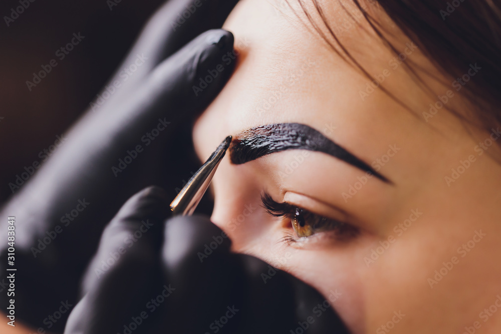Beautician applying henna to eyebrows (Adobe Stock comp)