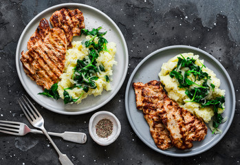 Roast pork with mashed potatoes and spinach - comfort winter meal on a dark background, top view