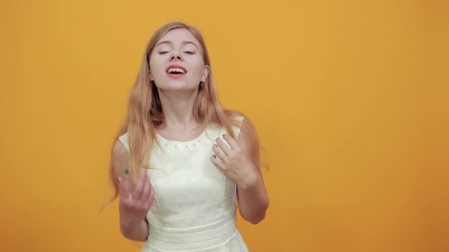 Disappointed caucasian young lady pointing finger at herself, looks questioningly at camera over isolated orange background wearing white shirt. Lifestyle concept