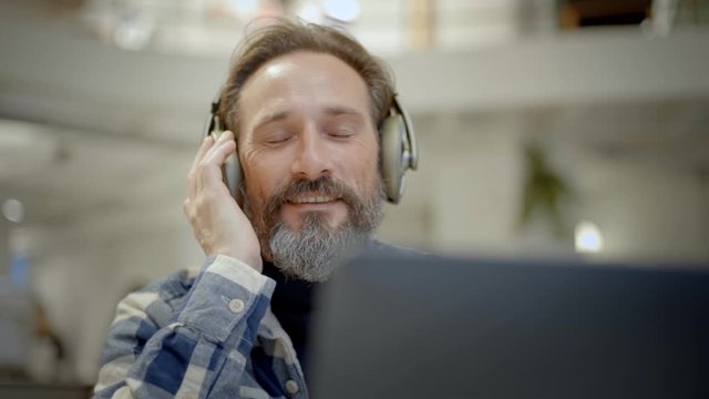 Real handsome adult man enjoys music in library