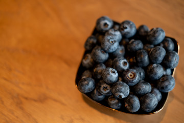 Fresh blueberries in the copper bowl on rustic natural wooden background