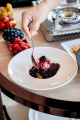 Chef's pouring mixed berries jam on compote and bread pudding