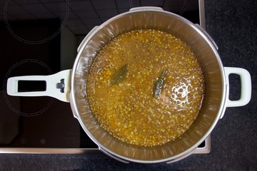 Lentils homemade soup fresh cooked - boiled into pressure cooker at home kitchen with leaves of bay ready to eat. Top view, soft focus at the foreground and background 