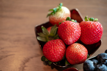 Fresh red strawberries in the copper bowl  on the wooden background