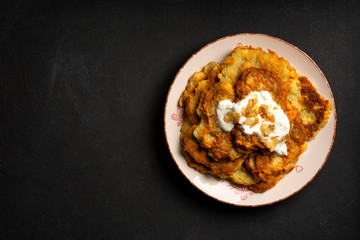 Exposition of home made potato pancakes on black table, traditional tasty food.
