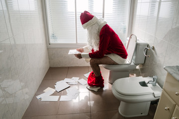 Santa Claus reading the children's letters as he sits on the toilet at home. © Xavier Lorenzo