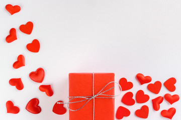 Festive composition from red gift box and hearts scattered on white background, valentines day concept, copy space