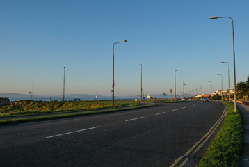 Sunlit road along the Wild Atlantic Way, going along Salthill promenade near Galway, in ireland. Tekan at sunrise on a sunny day.