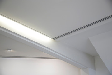 Girder between ceiling and wall. Abstract architecture fragment. Modern office building interior with polygonal white concrete elements. Diagonal geometric composition in light gray halftones.
