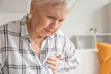 Senior woman suffering from heart attack at home