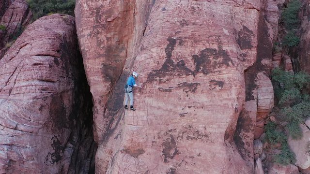 Aerial zoom out shot of female rock climber on the arete of a sandstone wall
