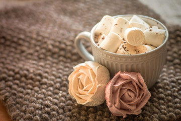 Obraz na płótnie Canvas cup of cocoa or hot chocolate next to rose-shaped marshmallow. Warm cozy square background.