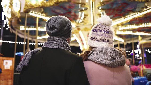 Loving couple on the background of winter holidays decorations during an evening walk around Christmas fair