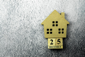 Small home mode and a vintage wooden calendar set at "25 December" on concrete floor.