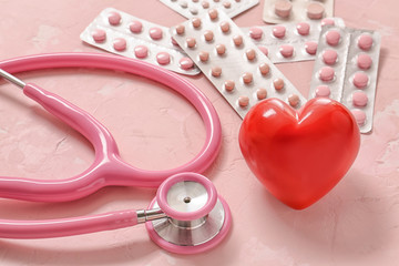 Stethoscope, heart and pills on color background. Cardiology concept