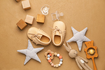 Baby booties with toys on color background