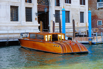 Fototapeta na wymiar Beautiful luxury wooden gondola on famous Grand Canal with traditional buildings and in summer day in Venice, Italy. Panoramic view of houses and boats on Canal Grande. Romantic city on water.