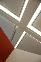 Drop ceiling lit by fluorescent lamps. Abstract architecture or modern office building interior with polygonal white elements. Diagonal geometric composition in lig