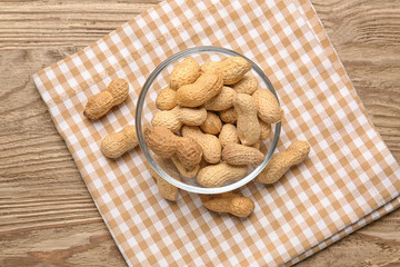 Bowl with peanuts on wooden table