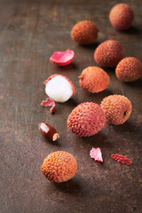 Lychee fruits, Fresh lychee and peeled showing the red skin and white flesh on a rusty dark background, top view, copy space.