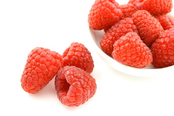 fresh red raspberry fruits in a small white bowl