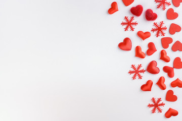 Festive composition from red hearts and snowflakes scattered on white background, valentines day concept, copy space