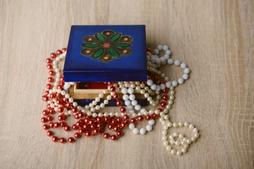 Gift box and red beads necklace on wooden background