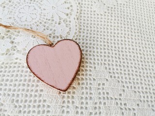 Single heart shaped wooden decorations on a white knitted background. Greeting card. Valentine's day concept. Copy space. 