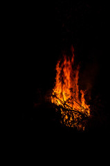 Bonfire burning trees at night. Large orange flame isolated on a black background. Fire on black. Brightly, heat, light, camping, big bonfire