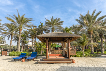 Bungalow with sun beds on a beautiful sandy beach with palm trees