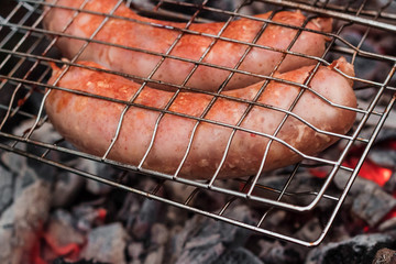 Sausages on the grill are grilled on the coals in the open air.