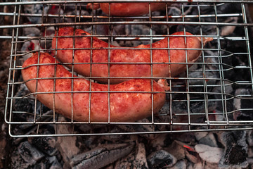 Sausages on the grill are grilled on the coals in the open air.