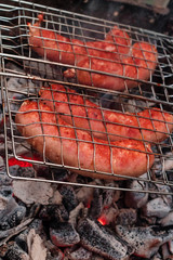 Sausages on the grill are grilled on the coals in the open air.