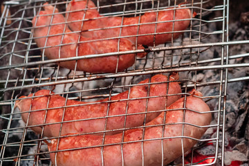 Sausages on the grill are grilled on the coals in the open air.