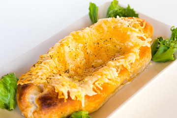 Georgian national pie khachapuri with cheese, butter and salad, on white plate.