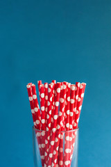 Red tubules for cocktails in a glass on a blue background