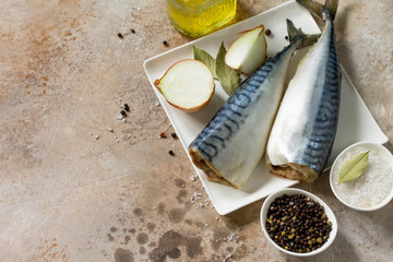 Fresh raw fish. Mackerel and ingredients for cooking on a stone countertop. Copy space.
