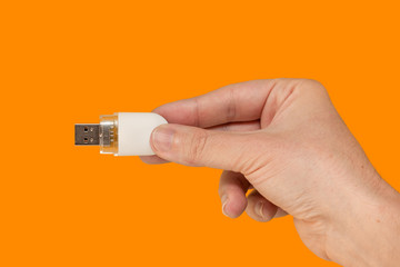 White USB Flash drive on hand with isolated orange background