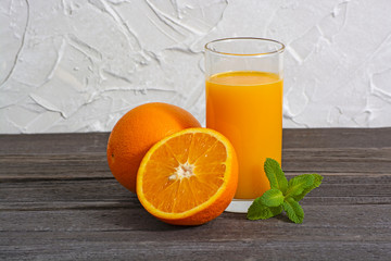 Orange juice in glass with mint, fresh fruits on wooden background