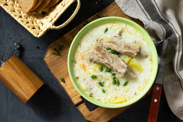 Hot homemade soup with meat ribs and vegetables on a stone countertop. Top view on a flat background lay.