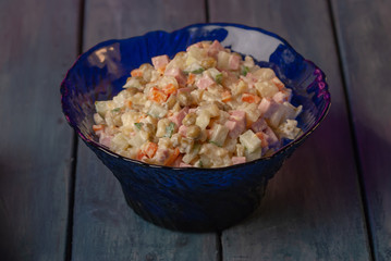 Olivier salad in a sapphire plate on a dark background