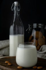 Transparent glass with milk, transparent bottle with milk, almonds and cookie jar