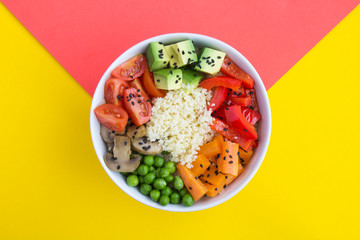 Vegan poke bowl with couscous  and vegetables in the white bowl in the center of the bicolor...