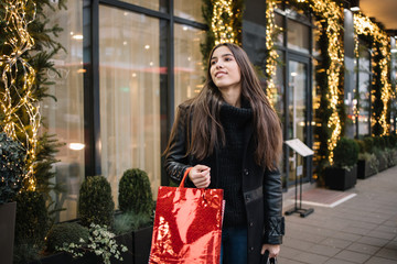 Girl with bags in front of building with lights
