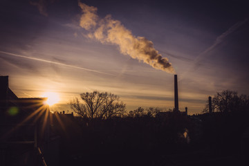 Image of industrial chimney and smoke during sunrise