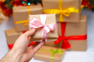 Boxes with gifts on a light, blue background and under the Christmas tree. Gift in the hand. Christmas presents, Nicholas Day, Valentine's Day. Bright boxes with bright ribbons Gifts in Macro.