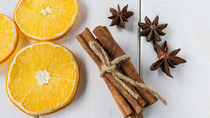 Dried lemon slices, anise starlets and cinnamon on a light wooden table