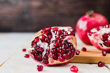 Whole fruit and halves of ripe pomegranate lie on a table on a wooden background. Organic Bio fruits