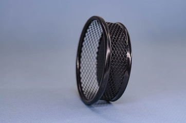 black basket in a mesh lying on its side on a blue background.